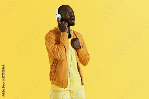 Quadro em tela Man in headphones listening music, singing to song portrait