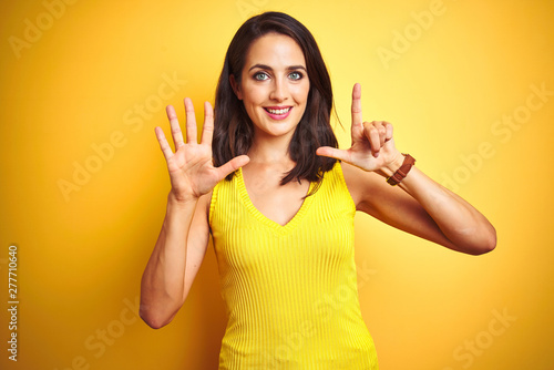 Young beautiful woman wearing t-shirt standing over yellow isolated background showing and pointing up with fingers number seven while smiling confident and happy.