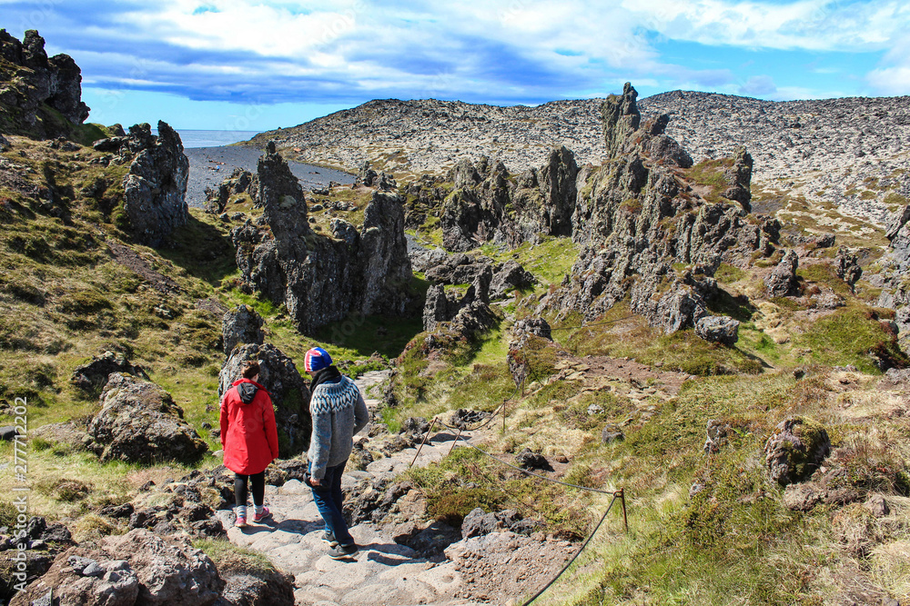 Hiking trail on rocky land on Djupalonssandur beach and hikers in Snaefellsjokull national park, Iceland