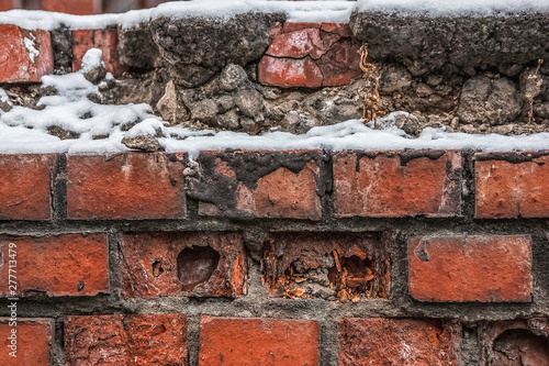 Destroyed brick wall in the street under the snow