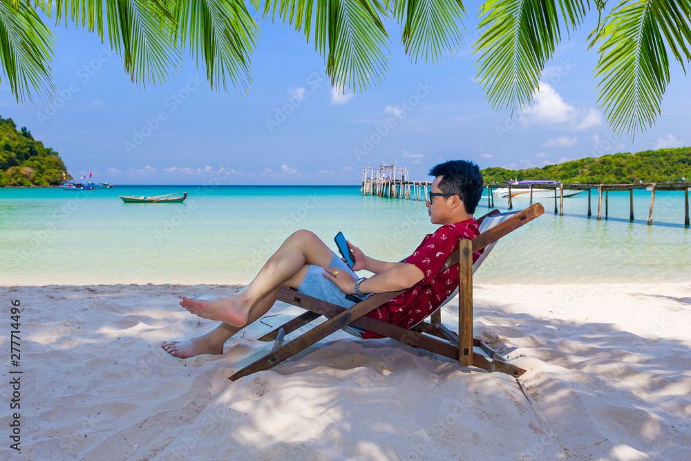 Obraz premium Man sitting on the beach at tropical sea.