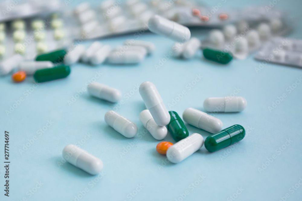 white, orange and green pill capsules falling on a blue background copy space white, orange and green pill capsules falling on a blue background copy space