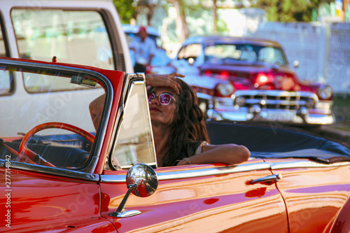 girl driving old orange car in Havana, Cuba © Alohadunya
