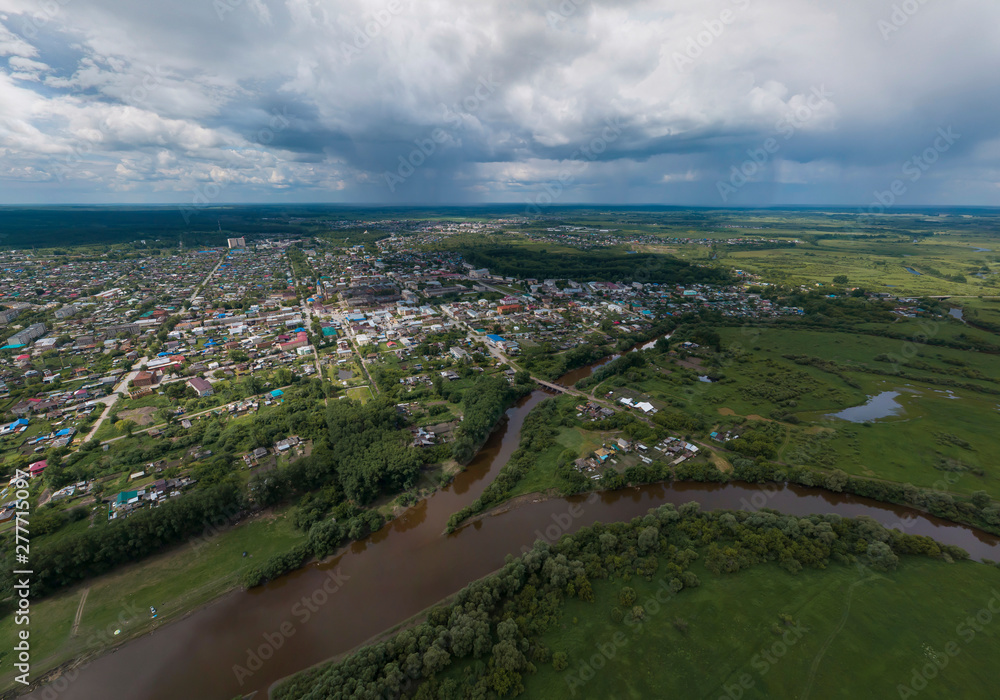 Irbit city and river. Russia. Aerial. Summer, cloudy.  A lots of trees and grass