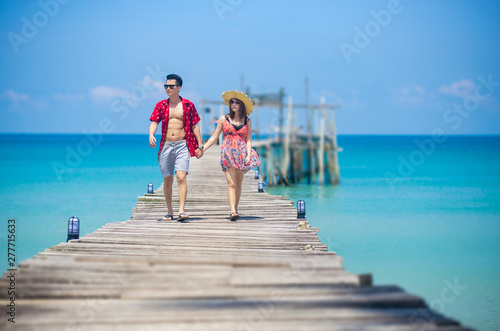 Lover couple honeymoon, walking on the wooden bridge at tropical sea. © Petch A Ratana