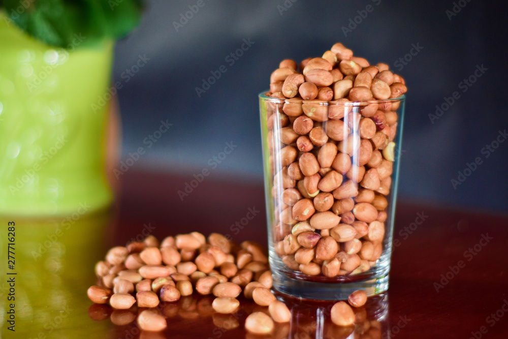 Peanut seeds in a glass of water and placed on a table, side view Peanut seeds in a glass of water and placed on a table, side view