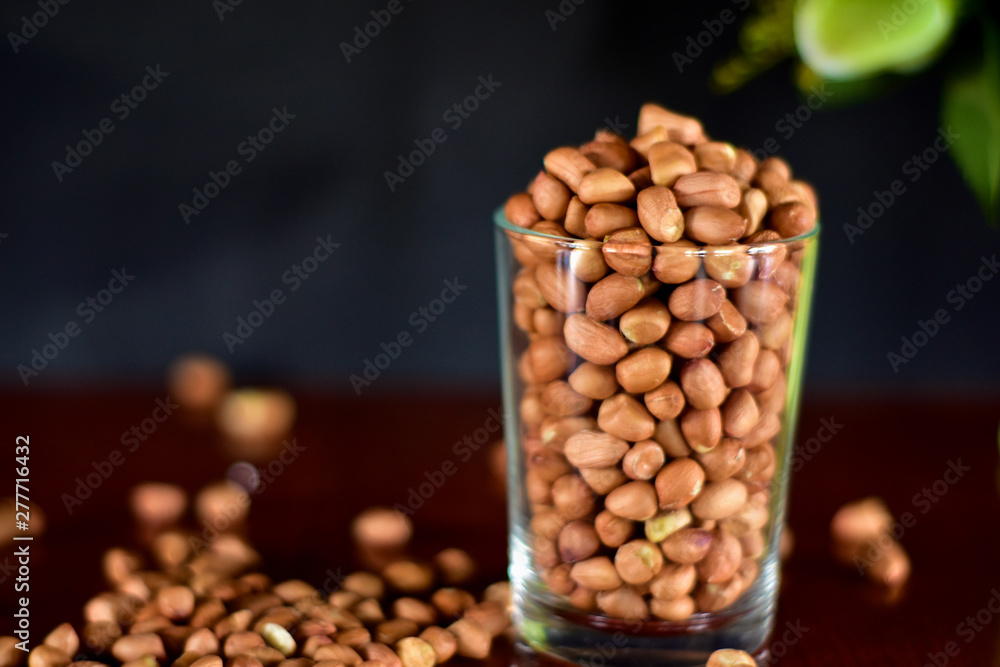 Peanut seeds in a glass of water and placed on a table, side view Peanut seeds in a glass of water and placed on a table, side view