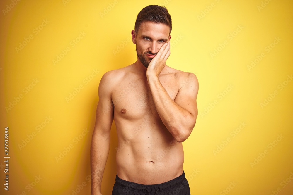 Young handsome shirtless man over isolated yellow background thinking looking tired and bored with depression problems with crossed arms.