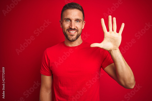 Young handsome man wearing casual t-shirt over red isolated background showing and pointing up with fingers number five while smiling confident and happy. © Krakenimages.com