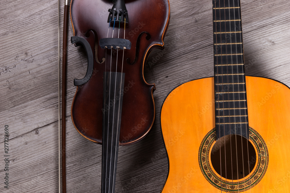 Naklejka premium Classical violin and guitar on wooden background. Traditional musical instruments