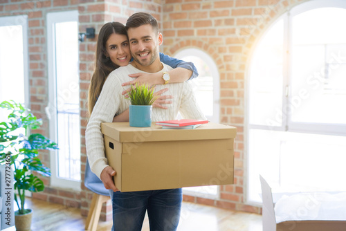 Beautiful young couple moving to a new house, smiling happy holding cardboard boxes at new apartment © Krakenimages.com