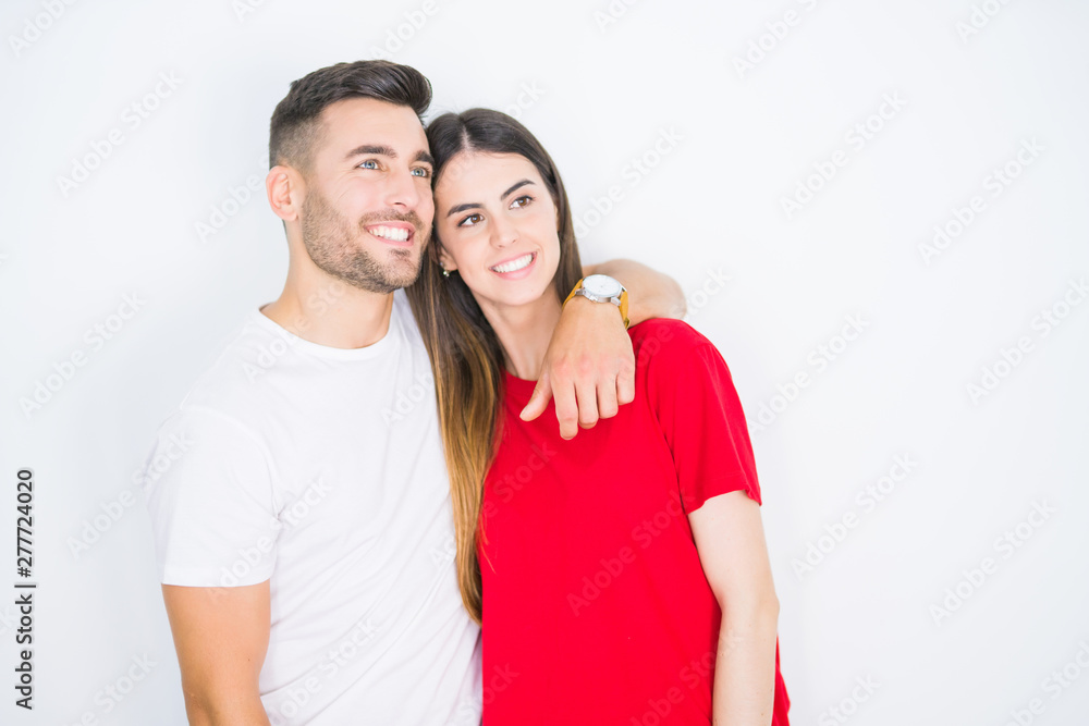 Young beautiful couple together over white isolated background looking away to side with smile on face, natural expression. Laughing confident.