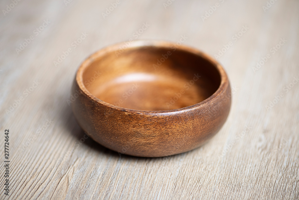 Close-up of brown wooden bowl on gray wooden table. Traditional rustic bowl. Close-up of brown wooden bowl on gray wooden table. Traditional rustic bowl.