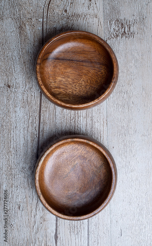 Vertical shoot of two brown wooden bowls on gray wooden table. Traditional rustic bowl.
