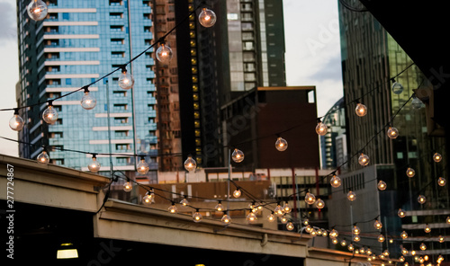 A hanging string of lights at Queen Victoria Markets with the skyline of Melbourne city in the background