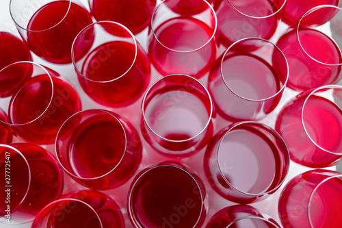 View from above at a a row of glasses filled with red wine are lined up ready to be served