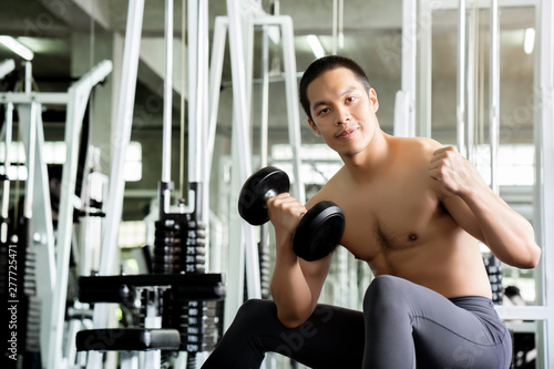 Daily exercise is popular for new generation, making the body healthy. And have good immunity Asian male trainer is playing an exercise machine in the gym to build muscle. To have a good looking shape