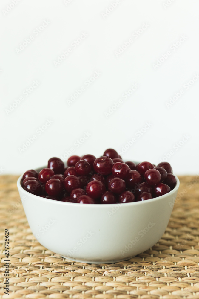 A plate full of fresh cherries on a natural wicker napkin A plate full of fresh cherries on a natural wicker napkin