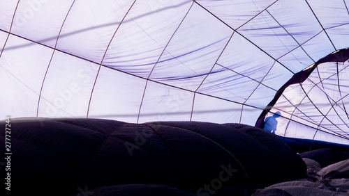 Clos-up of the inside of a blue hot air balloon with the silhouette of a man
