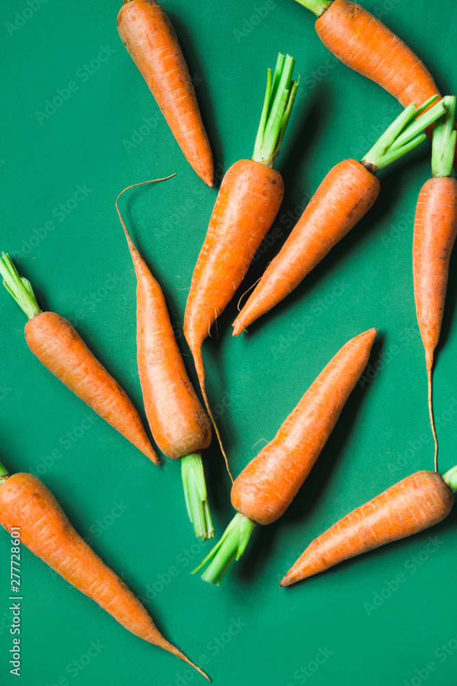 A few fresh carrots on green background. A few fresh carrots on green background.