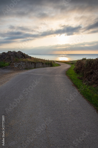 Vertical view of lonely local road with sunset on the sea in Cantabria  Spain  Europe