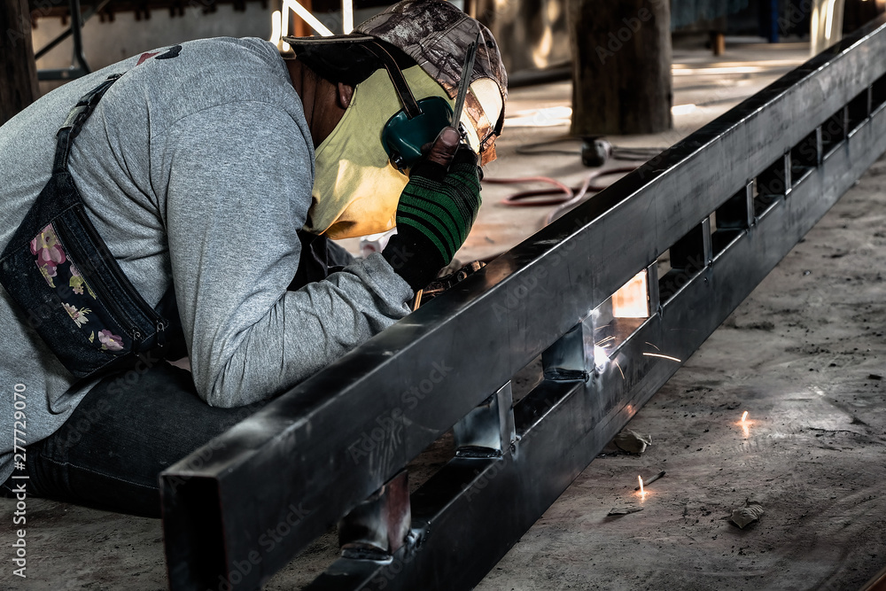 Industrial Worker at the factory welding closeup. Electric wheel grinding on steel structure in factory. Industrial Worker at the factory welding closeup. Electric wheel grinding on steel structure in factory.