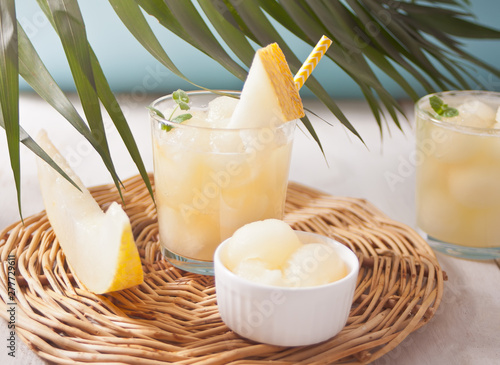 Glasses with melon cocktail on a white tablewith the palm leaf in tropical theme