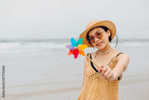 Woman enjoying beach relaxing joyful in summer by tropical blue water.Model on travel wearing beach hat.