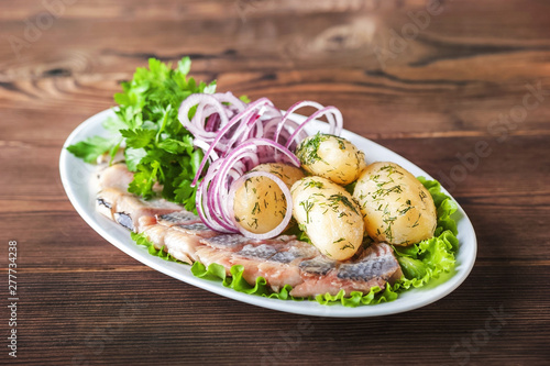 Russian cuisine in the form of potatoes with dill and herring in a white plate close-up. Potatoes with chopped herring and onions copy space.