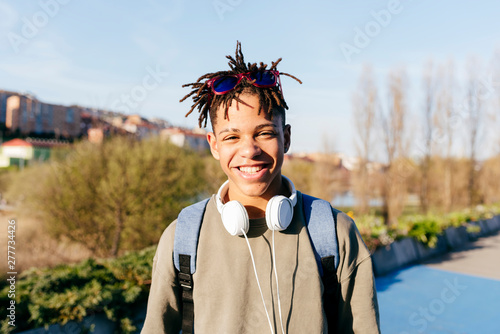 Young African American happy successful man in casual outfit with stylish sunglasses and headset on street looking at camera photo