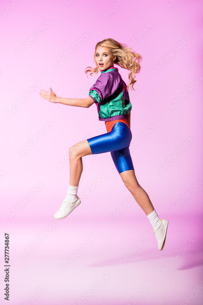 beautiful girl in sportswear jumping and gesturing on pink, doll concept