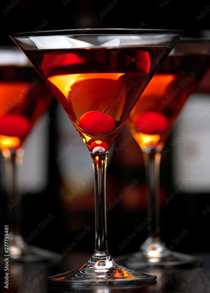 Close-up manhattan drinks with cherry with bar in the background