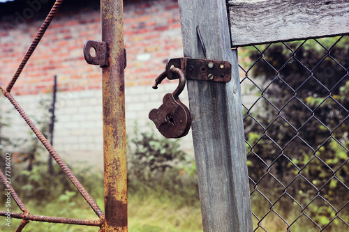 Rusty padlock open on old gate