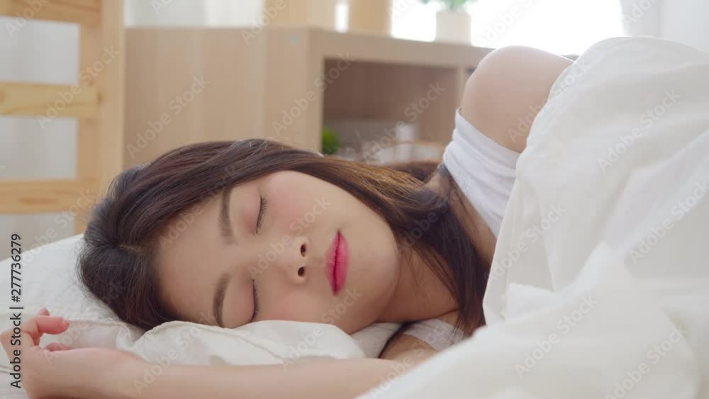 Slow motion - Beautiful attractive young Asian woman wake up, smiling and stretching her arms in her bed in bedroom. Young asia female use relax time at home. Lifestyle women relax at home concept. Slow motion - Beautiful attractive young Asian woman wake up, smiling and stretching her arms in her bed in bedroom. Young asia female use relax time at home. Lifestyle women relax at home concept.