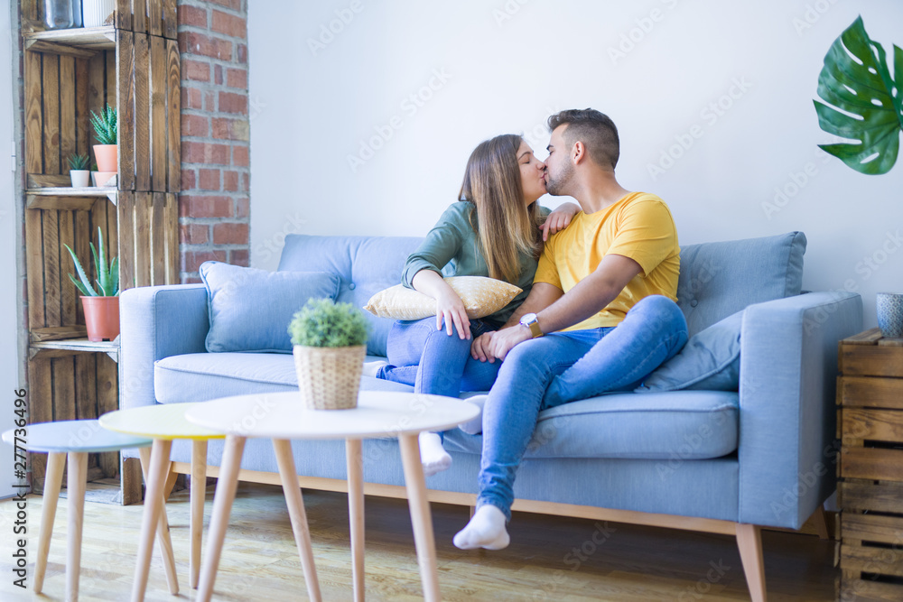 Obraz premium Young beautiful couple sitting hugging in love on the sofa at home