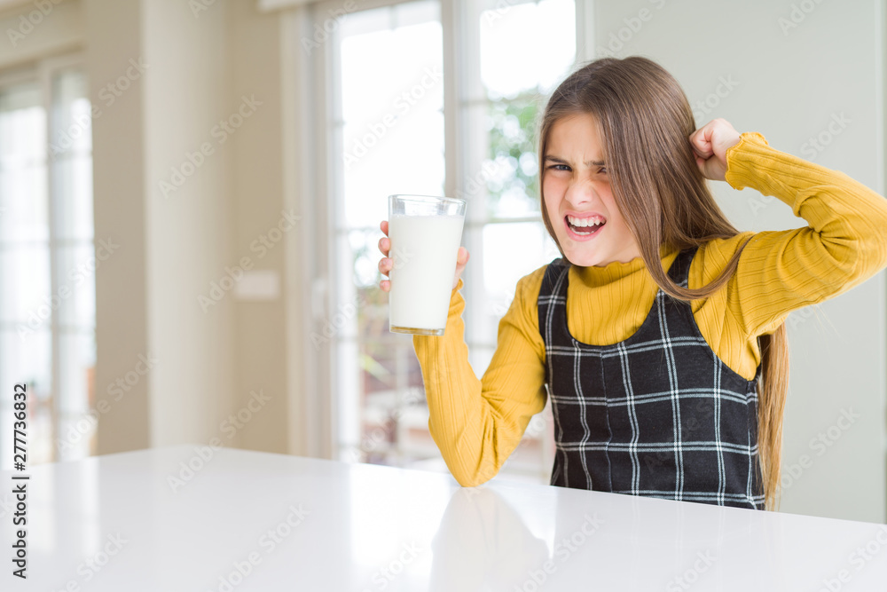 Beautiful young girl driking a glass of fresh milk annoyed and frustrated shouting with anger, crazy and yelling with raised hand, anger concept Beautiful young girl driking a glass of fresh milk annoyed and frustrated shouting with anger, crazy and yelling with raised hand, anger concept
