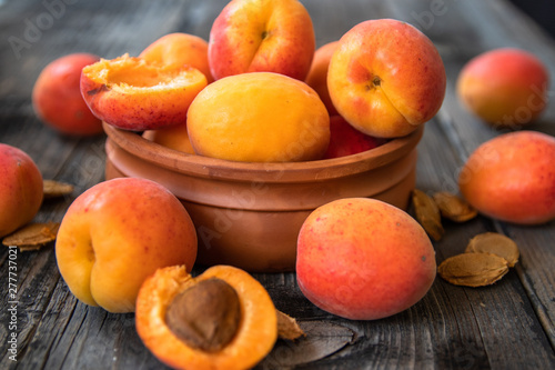 Fresh organic apricots in a clay bowl on old wooden table