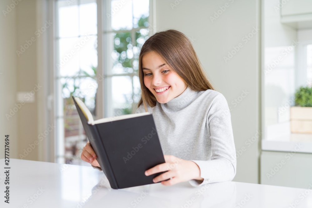 Beautiful young girl reading a book at home with a happy face standing and smiling with a confident smile showing teeth Beautiful young girl reading a book at home with a happy face standing and smiling with a confident smile showing teeth