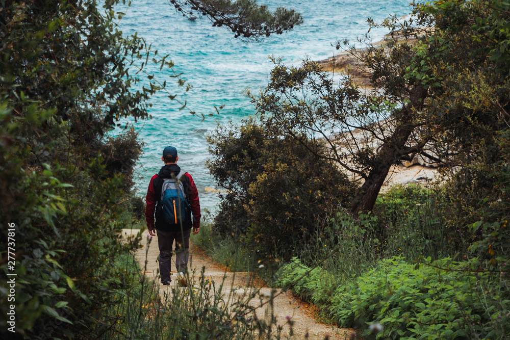 Obraz premium man walking by trial to sea beach overcast weather