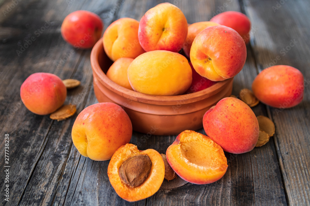Fresh organic apricots in a clay bowl on old wooden table