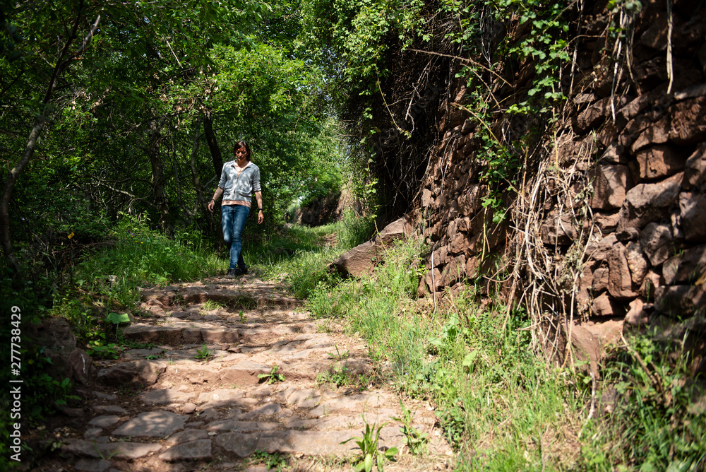 Woman walking on a mountain trail with stone handmade walls. Woman walking on a mountain trail with stone handmade walls.