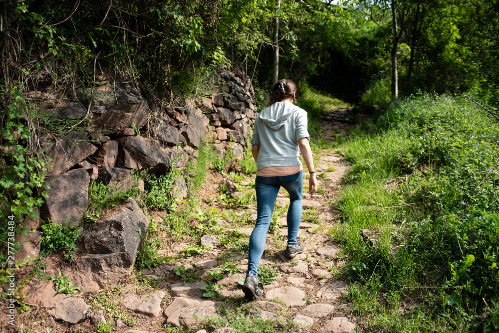 Woman walking on a mountain trail with stone handmade walls. Woman walking on a mountain trail with stone handmade walls.