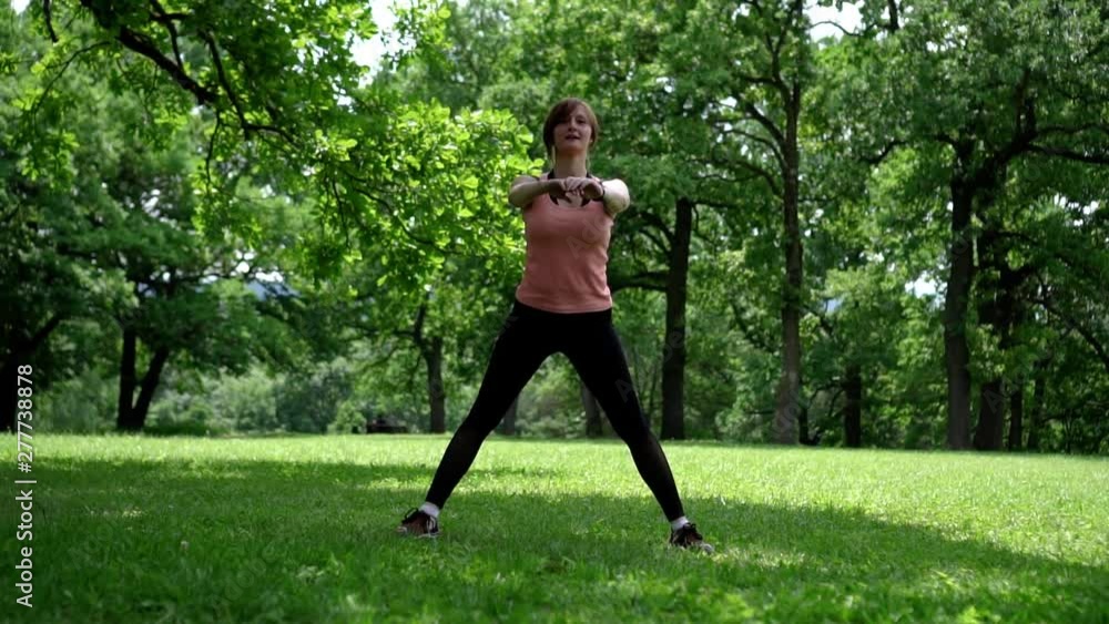 girl doing squats in the park on the grass