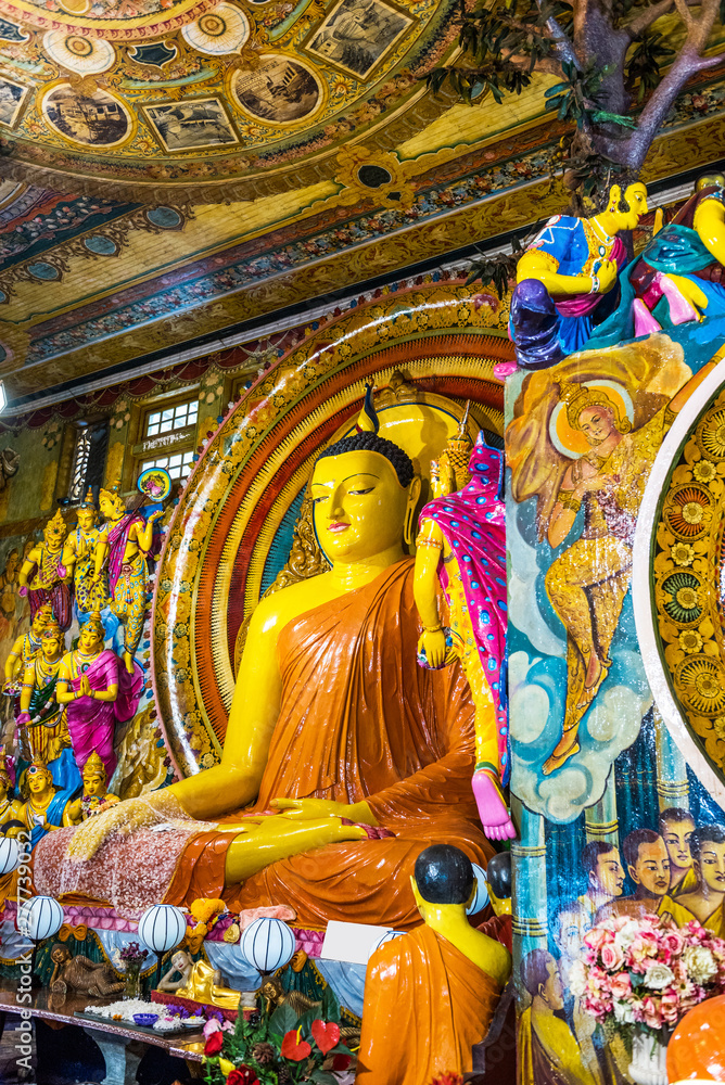 Fototapeta premium Buddha statue inside Gangaramaya Temple, Colombo, Sri Lanka. Vertical.