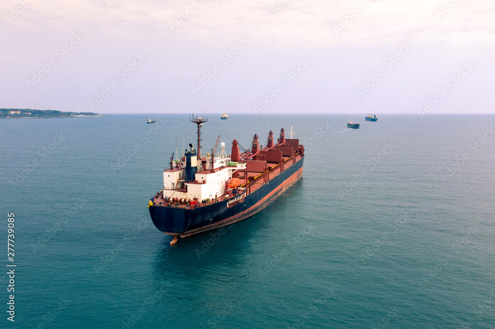 Aerial view of high-speed sea vessel for transportation of a cargo vessel at high speed is drifting near the seaport of the city at sunset. Ship on the background of blue sea water. Import, export Aerial view of high-speed sea vessel for transportation of a cargo vessel at high speed is drifting near the seaport of the city at sunset. Ship on the background of blue sea water. Import, export