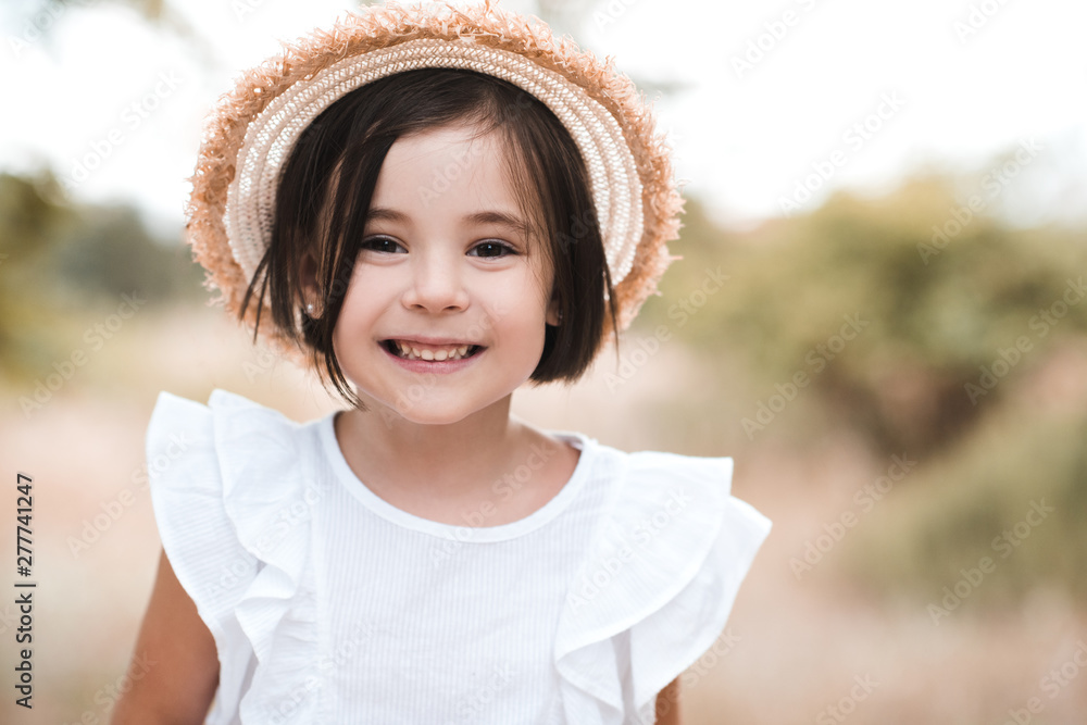 Smiling kid girl 3-4 year old wearing straw hat and white stylish shirt ...