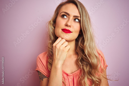 Young beautiful woman wearing t-shirt standing over pink isolated background serious face thinking about question, very confused idea