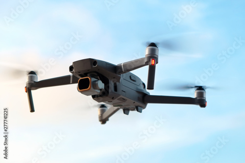 Professional filming drone flies in the air at a low altitude against a blue sky. Drone makes photos. Modern new technology. Ready background with place for your text.