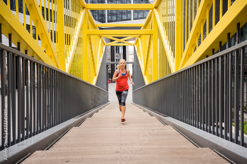 European Quarter, Stuttgart, Baden-W¸rttemberg, Germany: A female runner running up stairs covered in a fancy, yellow steal construction.           photo