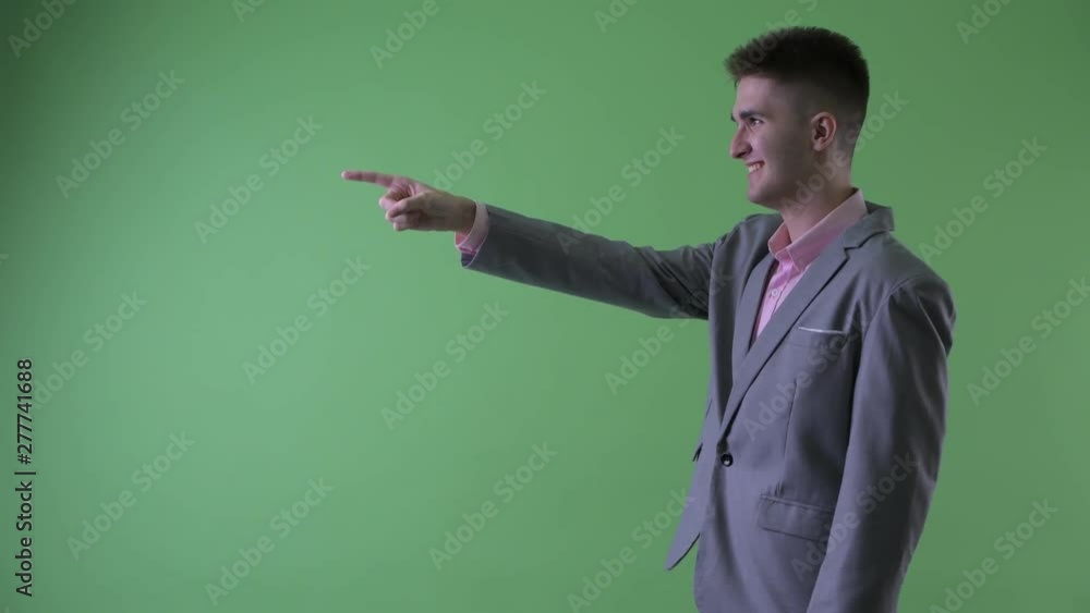 Profile view of happy young businessman pointing finger Profile view of happy young businessman pointing finger